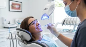 Professional in-office teeth whitening treatment being performed by a dentist in a clinical setting.